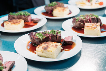 Tranchiertes Rinderfilet auf Teller mit Kartoffelgratin und Sauce