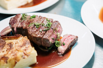 Tranchiertes Rinderfilet auf Teller mit Kartoffelgratin und Sauce