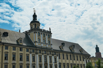 Fototapeta premium Grand baroque university building stands prominently under a partly cloudy sky, highlighting the academic and architectural legacy of Wroclaw, Poland in a historic urban setting.