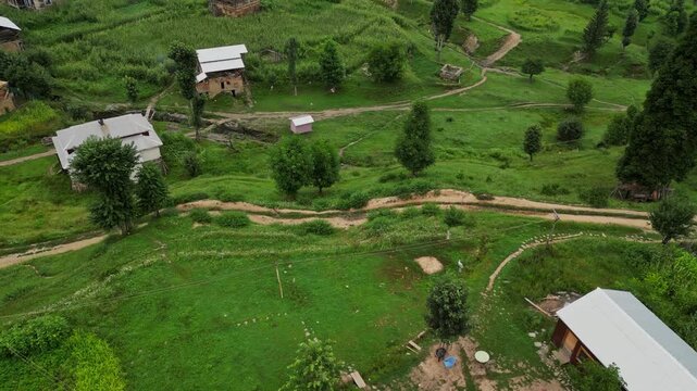 Aerial View of Arang Kel, Azad Kashmir &mdash; Scenic Mountain Village with Colorful Houses, Lush Greenery, and Misty Hills Surrounded by Dense Pine Forests on a Cloudy Day