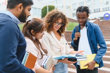 Fototapeta premium Diverse students reviewing book together on campus