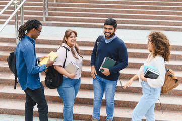 Fototapeta premium Diverse college students talking on university campus stairs