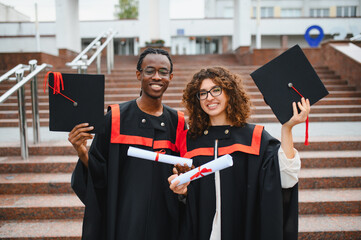 Diverse students celebrating graduation, holding diplomas and caps