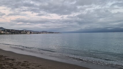 There is a man walking along the beach with a surfboard