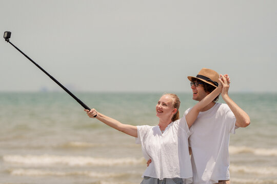 Happy young couple enjoying playful piggyback ride at the beach during sunset. Perfect for concepts like romance, summer vacation, freedom, fun, and relationship lifestyle imagery.