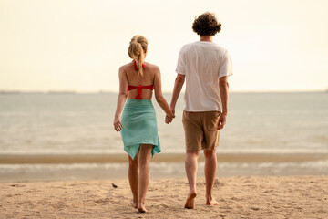Happy young couple enjoying playful piggyback ride at the beach during sunset. Perfect for concepts like romance, summer vacation, freedom, fun, and relationship lifestyle imagery.