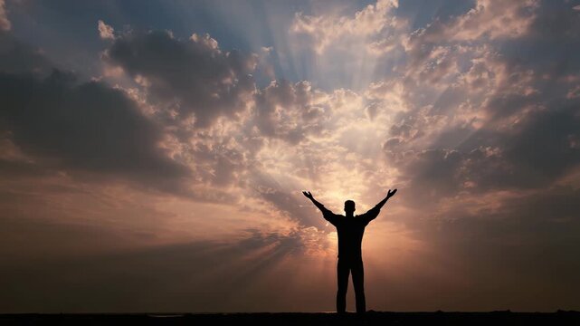 silhouette of person raising hands to dramatic sky with sun rays spiritual freedom hope and gratitude concept