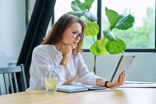 Middle aged female teacher entrepreneur using digital tablet for video online meeting