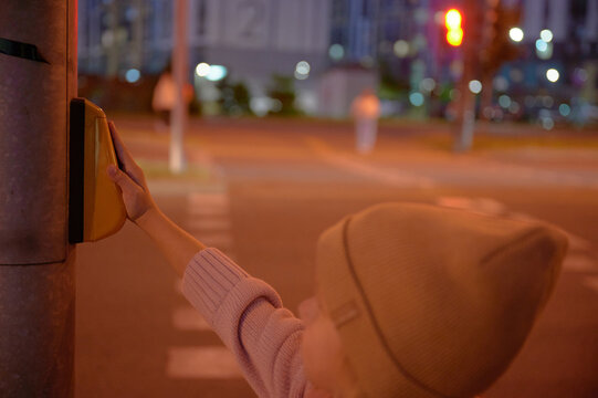 Pedestrian pressing street crossing button at night