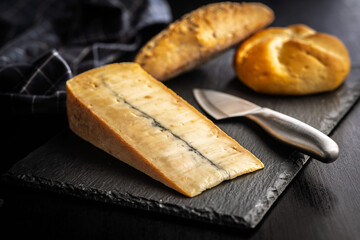 Morbier cheese. Delicious french cheese with mold on black table.