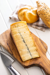 Morbier cheese. Delicious french cheese with mold on cutting board on white table.