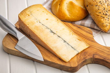 Morbier cheese. Delicious french cheese with mold on cutting board on white table.