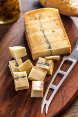 Morbier cheese. Delicious french cheese with mold on cutting board on wooden table.