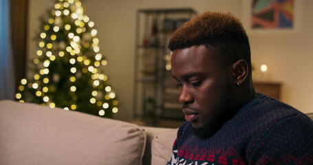 Young man is typing on laptop keyboard. The boy is dressed in warm holiday sweater, has watch on...