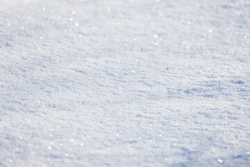 A sunlit, snow-covered ground glistens with tiny crystals, background photo texture