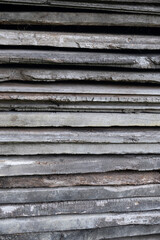 Close-up of stacked rough wooden planks with weathered texture and cracks. Rustic background with natural grain, ideal for design, construction, or eco-themed concepts.