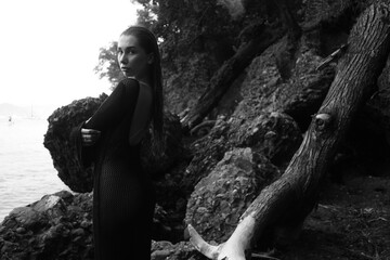 black and white portrait of woman in bikini on tropical beach near the mountain	
