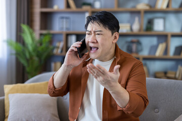 Asian man stressing during angry phone call argument