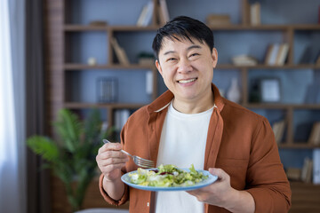 Happy asian man eating fresh healthy salad