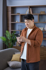 Asian man smiling using smartphone at home