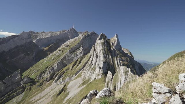 Altenalpt&uuml;rme limestone towers from Sch&auml;fler ridge, steep grass slopes under clear blue summer sky with S&auml;ntis vista; ideal for adventure travel and outdoor brands.