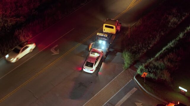 Car accident on American street. Tow truck picking up destroyed car and emergency services helping victims of vehicle crash on road in USA.