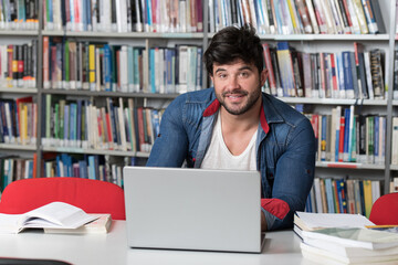 Happy Male Student With Laptop in Library
