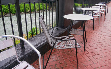 A tables in a street cafe near the river, rainy day. The cafe is empty. Nobody, no people