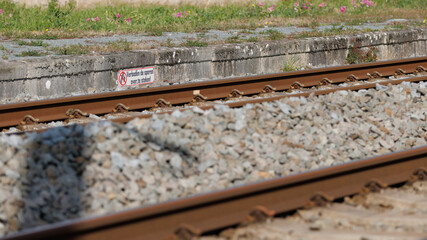 Naklejka premium Cautionary sign near train tracks emphasizes safety importance for travelers