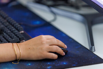 Focused hand navigating digital space with modern mouse and keyboard on cosmic desk mat