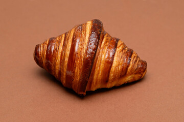 Glossy butter croissant on a brown background