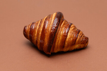 Glossy butter croissant on a brown background