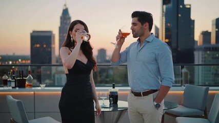 Couple toasting cocktails on a rooftop at sunset