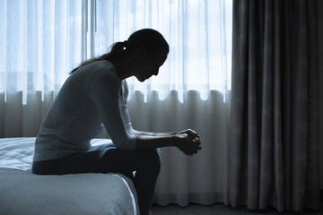 Silhouette depressed woman sadly sitting on the bed in the bedroom. Sad man suffering depression insomnia awake and sit alone on the bed in bedroom. Depression health people concept. 