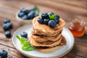 Stack of healthy gluten free oat pancakes served with fresh blueberries and honey