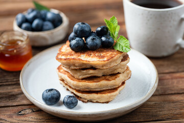 Stack of healthy gluten free oat pancakes served with fresh blueberries and honey