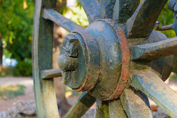 Close-up of vintage wagon wheel with weathered wood and rusted metal details in a peaceful garden setting