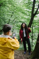 Father photographing daughter enjoying outdoor forest hike