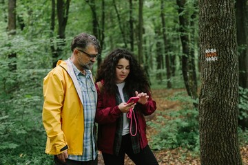 Father daughter hiking forest using smartphone navigation