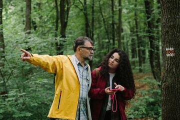 Obraz premium Father guiding daughter exploring forest hiking trail