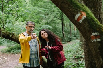 Father and daughter navigating forest path on a hike