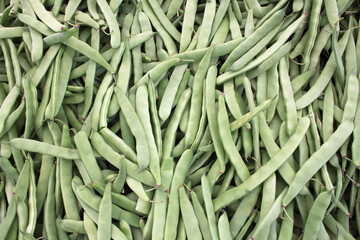 Fresh green beans in pods stacked at the market.