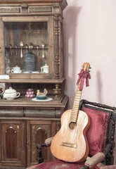 A room with an antique carved wardrobe and an antique guitar