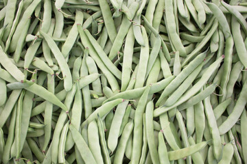 Fresh green beans in pods stacked at the market.
