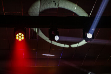 Luzes de palco, com fachos e projeções de luzes no teto escuro de um teatro. © Angela