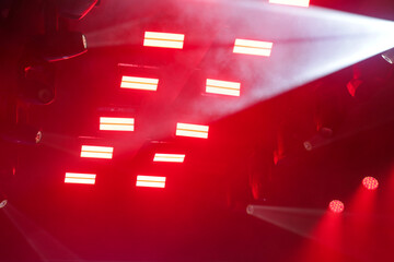 Foto de conjunto de luzes de palco, com fachos de luzes nas cores vermelha e branca. © Angela