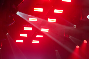 Foto de conjunto de luzes de palco, com fachos de luzes nas cores vermelha e branca. © Angela