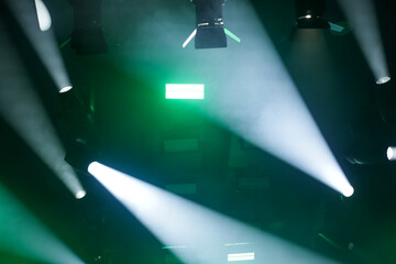 Foto de conjunto de luzes de palco, com fachos de luzes nas cores verde e branca. © Angela