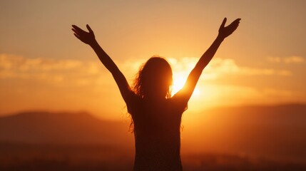 Fototapeta premium A figure stands with arms raised in celebration during sunset, surrounded by a breathtaking orange and yellow sky. The silhouette creates a feeling of joy at the days end.