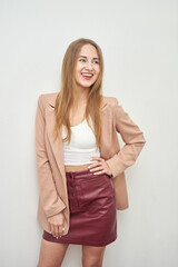 Fototapeta premium Smiling young caucasian female in blazer and skirt posing against white wall.